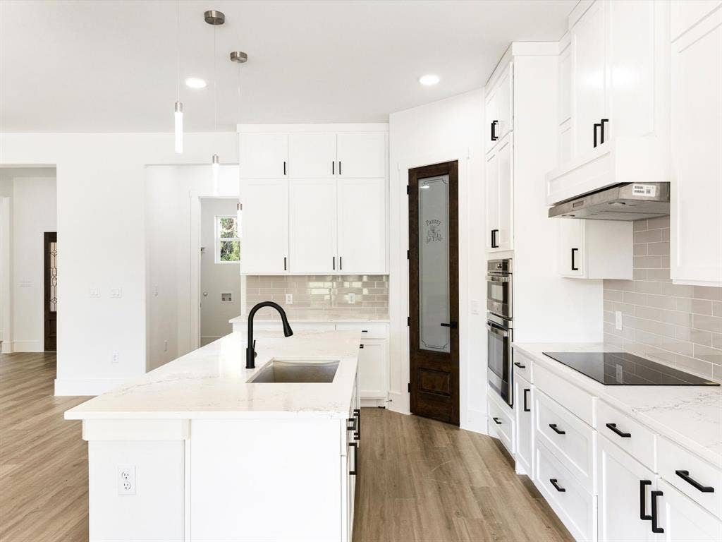 475 Loren Boyd Road, Combine, TX 75159 Kitchen featuring white cabinetry, quartz countertops, a central island with a matte black faucet, integrated stainless steel double wall ovens, and wood-finish flooring