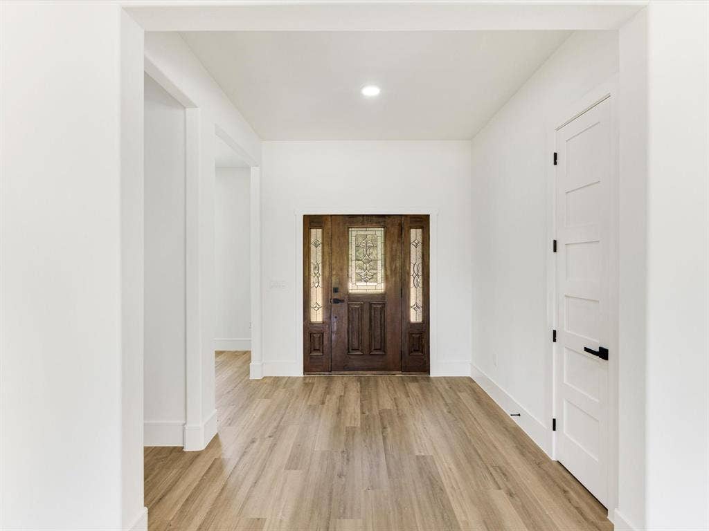 475 Loren Boyd Road, Combine, TX 75159 Entryway featuring wood-finish flooring, a solid wood-stain entry door with decorative glass inserts, and a white five-panel interior door with matte black hardware