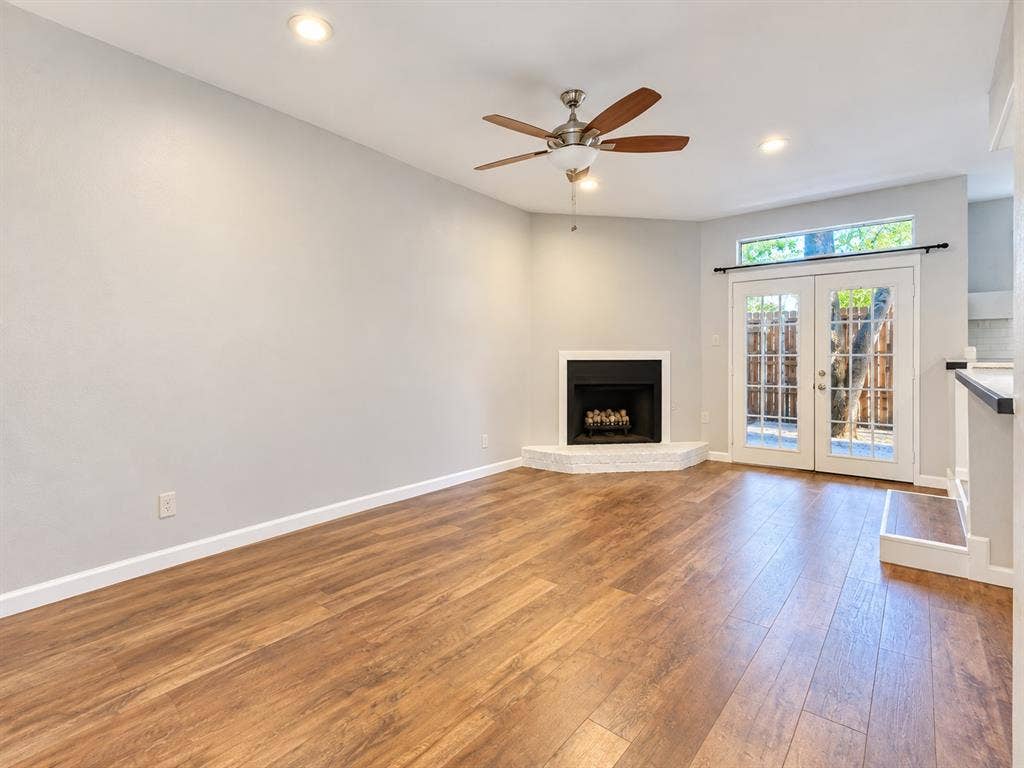 7525 Holly Hill Drive, #3, Dallas, TX 75231 Living area featuring wood-finish flooring, a corner fireplace with a raised hearth, recessed lighting, a ceiling fan, and glass-paned double doors