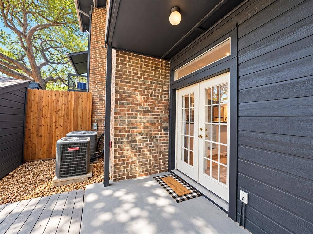 7525 Holly Hill Drive, #3, Dallas, TX 75231 Covered exterior patio featuring horizontal siding, exposed brick masonry, French doors with glass panes, and a transom window