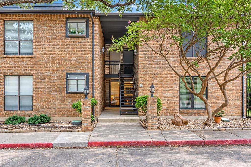 7525 Holly Hill Drive, #3, Dallas, TX 75231 Multi-story brick exterior featuring a recessed entrance, black metal staircase, multi-pane windows, and exterior light fixtures