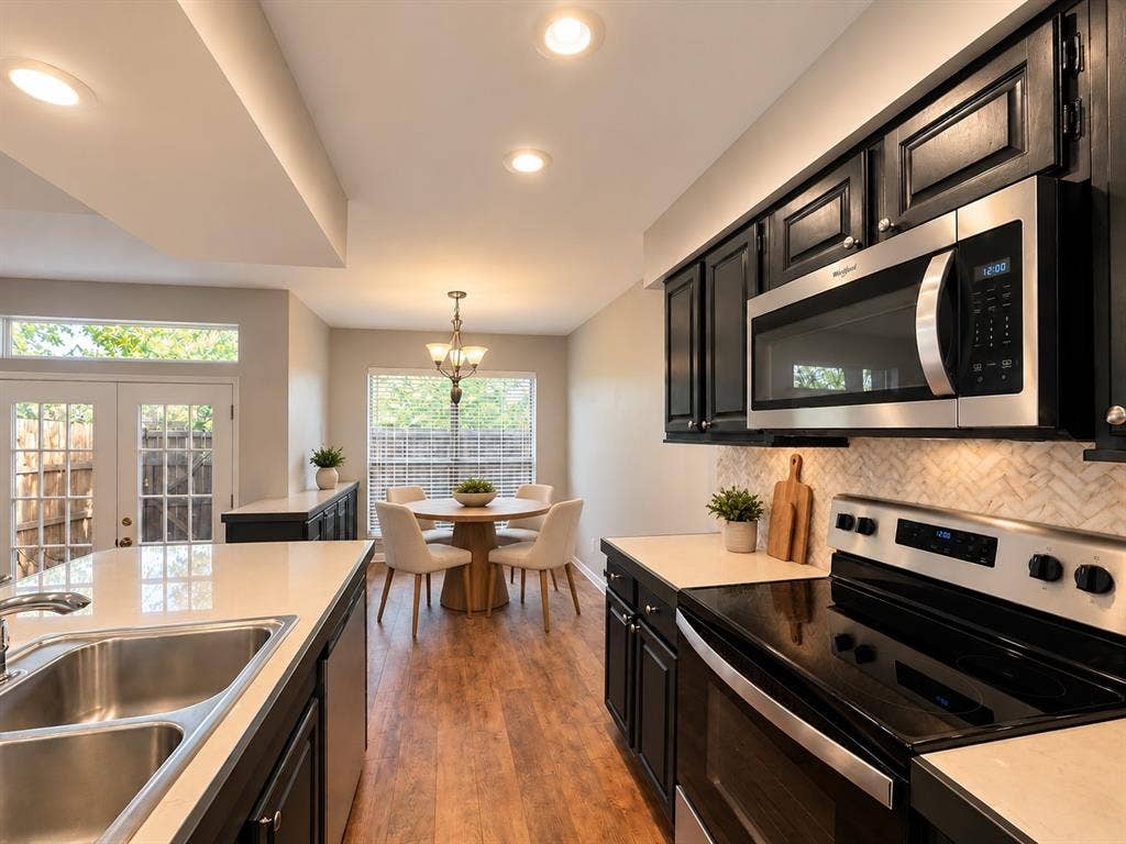 7525 Holly Hill Drive, #3, Dallas, TX 75231 Kitchen featuring dark cabinetry, stainless steel appliances, herringbone-patterned backsplash, light-toned countertops, and wood-finish flooring
