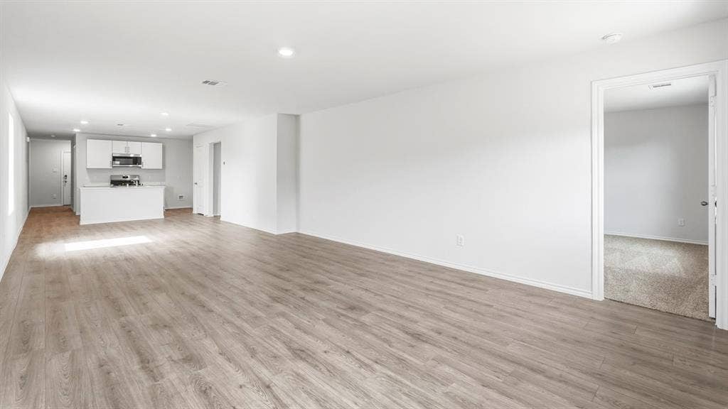 Spacious living area with wood-finish flooring, recessed lighting, and a white color palette