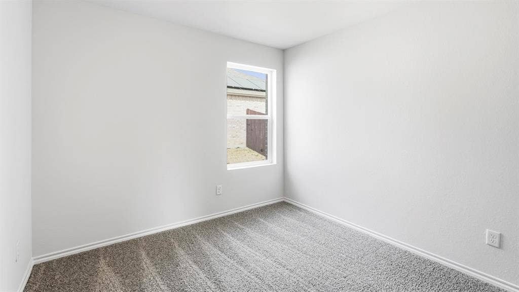 Neutral wall paint, window with white trim, and gray carpeted flooring