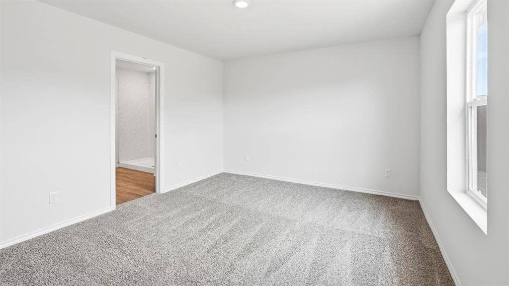 Carpeted room with white walls, recessed lighting, and a single window