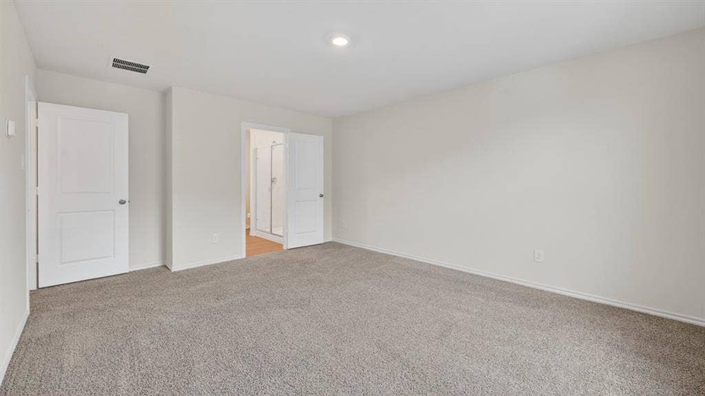 Spacious room featuring neutral carpeting, light-toned walls, and recessed lighting