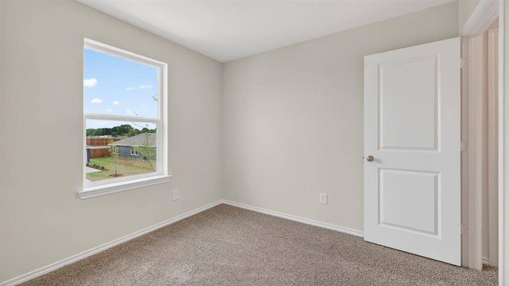 Room featuring a window with white trim, light gray walls, and textured carpet flooring