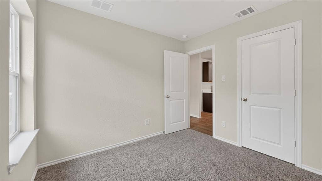 2825 Selfridge Lane, Forney, TX 75126 Light gray walls, window with white trim, gray carpet, and white two-panel doors