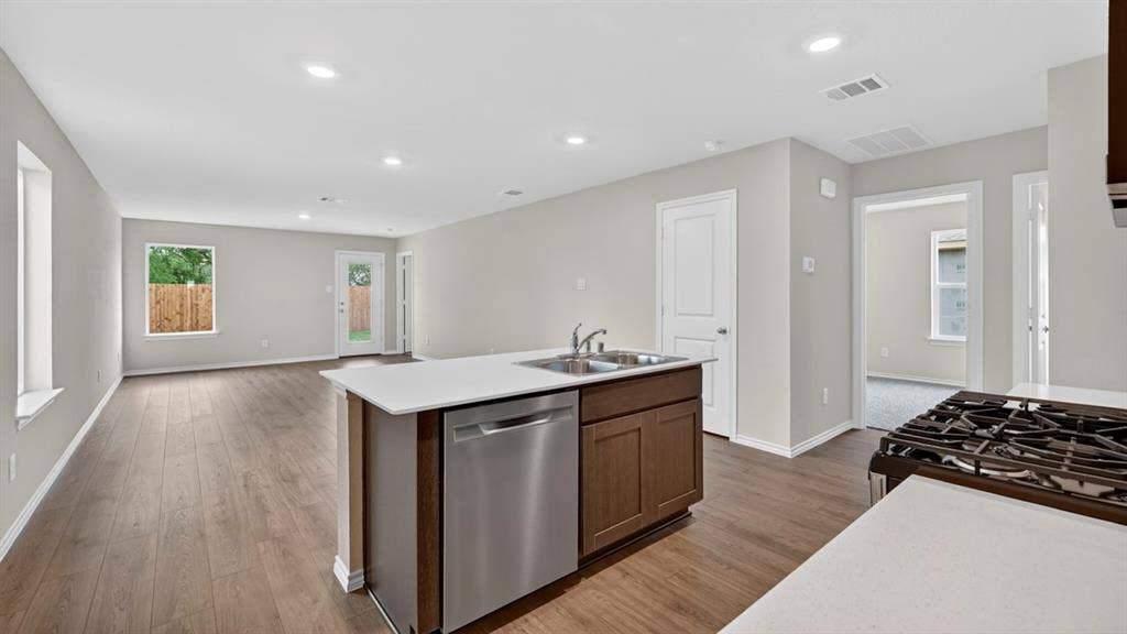2825 Selfridge Lane, Forney, TX 75126 Open-concept living space featuring wood-finish flooring, recessed lighting, and an island with an integrated stainless steel sink and dishwasher