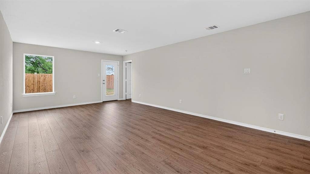 2825 Selfridge Lane, Forney, TX 75126 Spacious room featuring wood-finish flooring, neutral-toned walls, a bright window, and a glass-paneled door