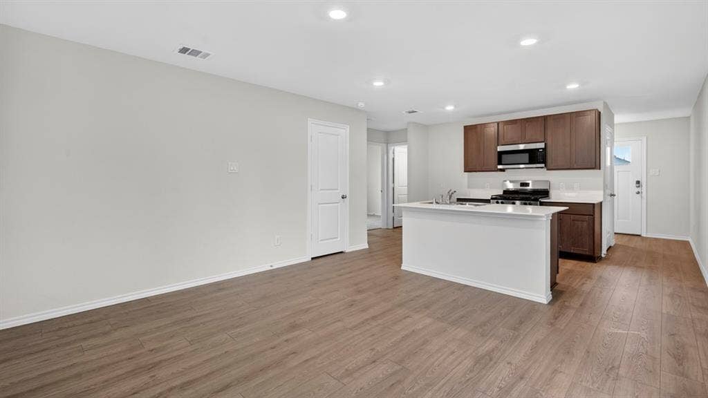 2825 Selfridge Lane, Forney, TX 75126 Open-concept living space featuring wood-finish flooring, recessed lighting, a kitchen island with a white countertop, and dark wood cabinetry