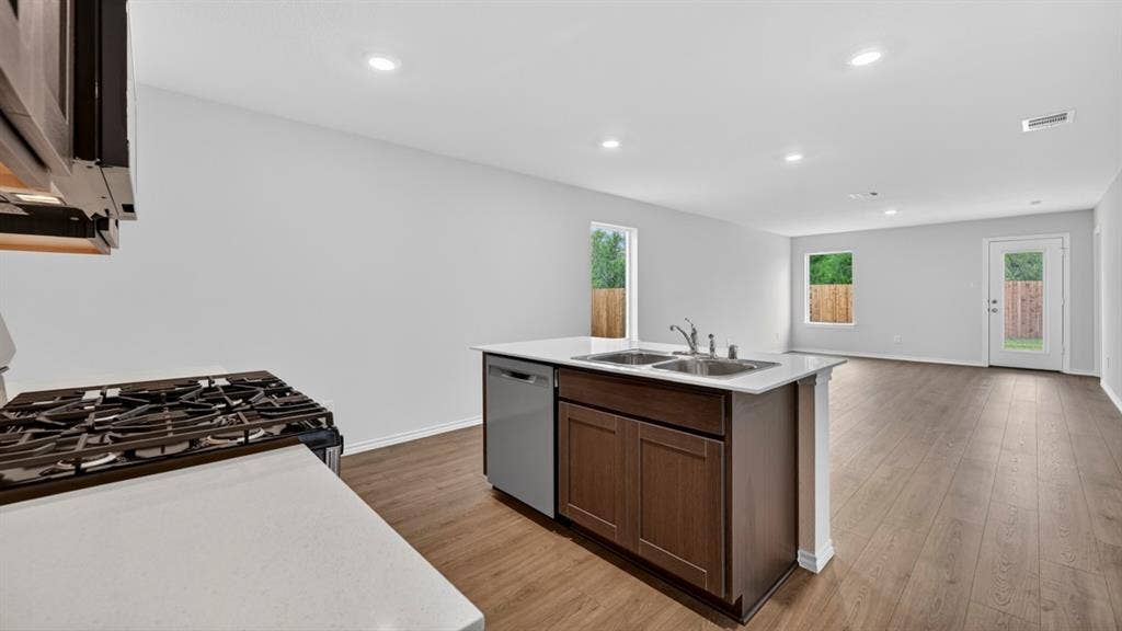 2825 Selfridge Lane, Forney, TX 75126 Kitchen island with dual stainless steel sink, wood-finish cabinetry, and integrated dishwasher