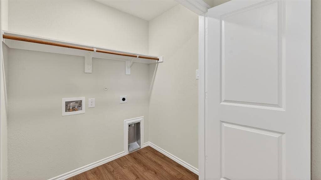 2825 Selfridge Lane, Forney, TX 75126 Laundry area featuring wood-finish flooring, a built-in shelving unit, and a white paneled door