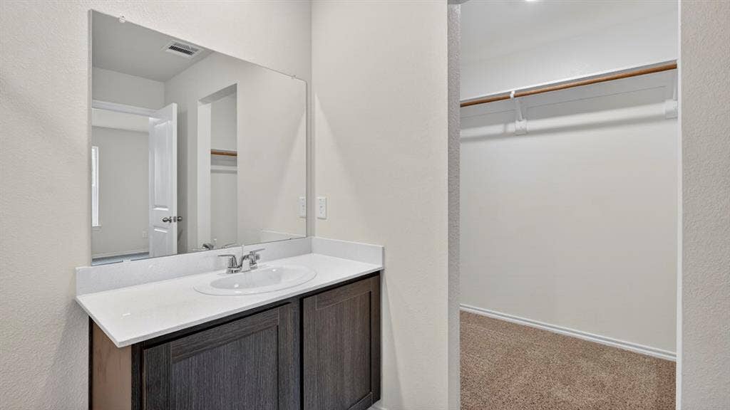 2825 Selfridge Lane, Forney, TX 75126 Bathroom vanity with an integrated sink, polished chrome faucet, and dark wood-finish cabinetry
