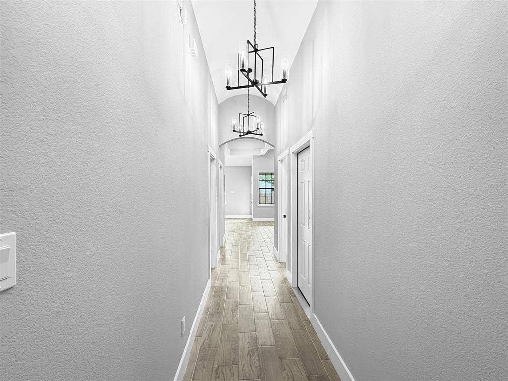 3025 Red Oak Drive, Granbury, TX 76048 Hallway featuring a barrel-vaulted ceiling, wood-finish flooring, and dual geometric-frame chandeliers