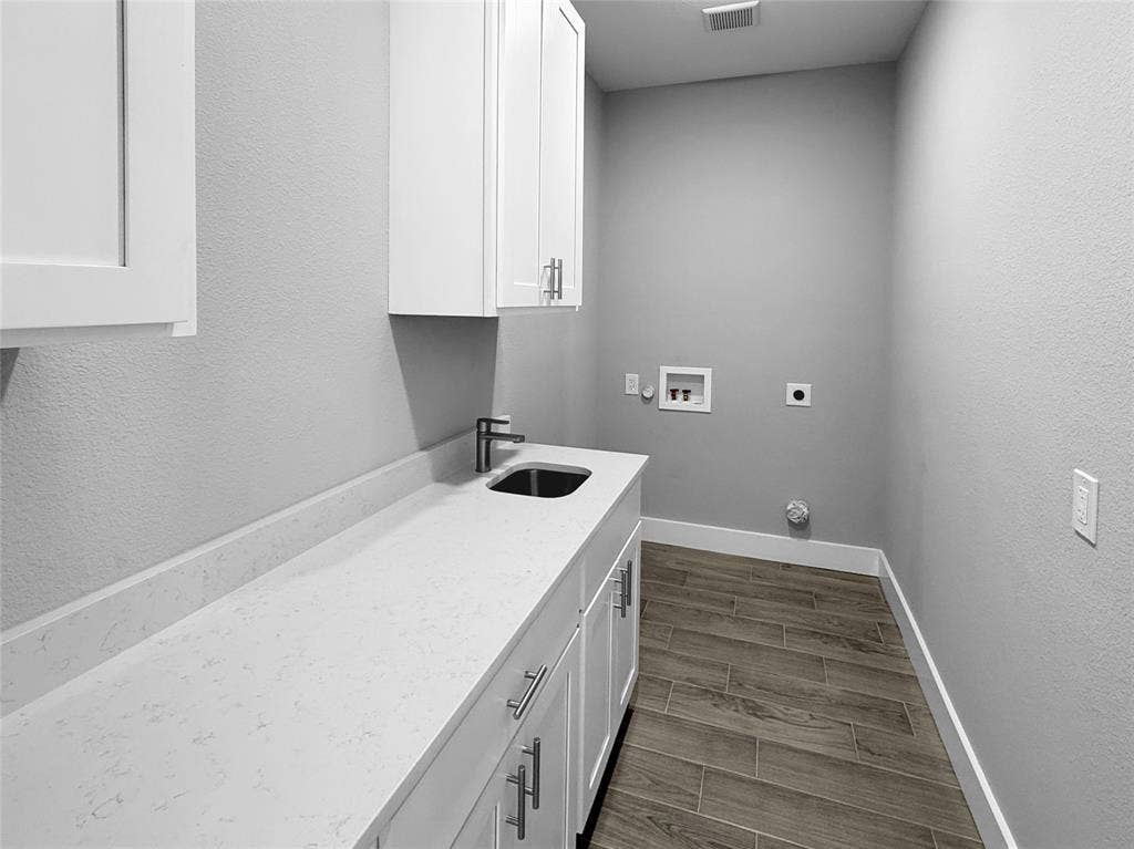 3025 Red Oak Drive, Granbury, TX 76048 Utility space featuring white shaker-style cabinetry, solid-surface countertop, undermount sink with metal faucet, and wood-finish tile flooring