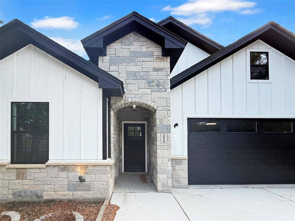 3025 Red Oak Drive, Granbury, TX 76048 Exterior featuring board and batten siding, masonry facade, dual-pitched roofline, contrast trim, and a concrete driveway