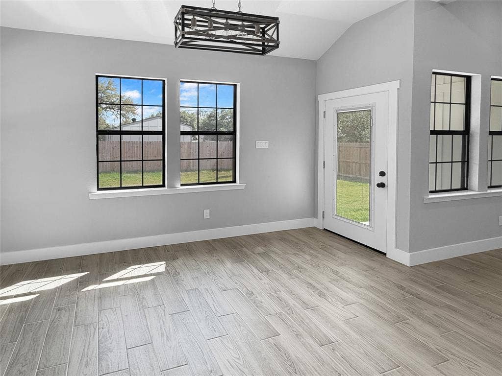3025 Red Oak Drive, Granbury, TX 76048 Vaulted ceilings, wood-finish flooring, rectangular windows with black frames, and a geometric metal chandelier