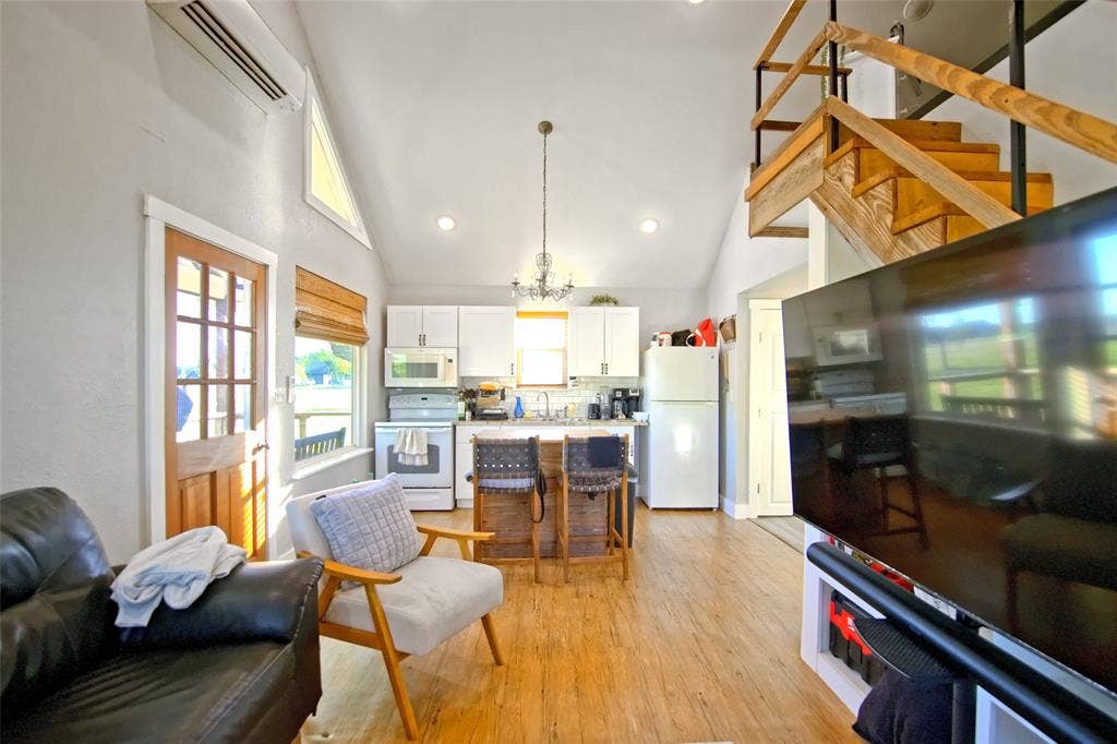 325 & 321 Grassy Way, Elm Mott, TX 76640 Vaulted ceilings with recessed lighting, wood-finish flooring, white kitchen cabinetry, and an open timber staircase