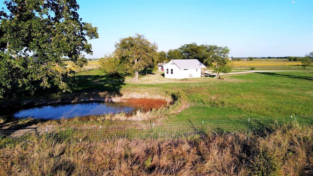325 & 321 Grassy Way, Elm Mott, TX 76640 Expansive rural acreage featuring a detached structure, a natural pond, mature trees, and wire perimeter fencing