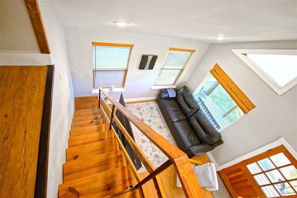325 & 321 Grassy Way, Elm Mott, TX 76640 Wood-tread staircase with a structural wood railing, multiple large windows providing natural light, recessed lighting, and a distinct triangular window feature