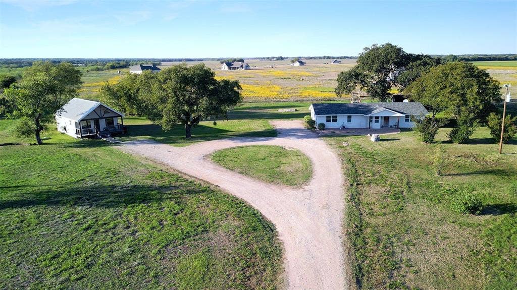 325 & 321 Grassy Way, Elm Mott, TX 76640 Expansive acreage featuring two detached structures, a gravel circular driveway, mature trees, and open pasture land
