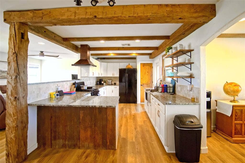 325 & 321 Grassy Way, Elm Mott, TX 76640 Exposed heavy timber beam ceiling accents, kitchen island with wood-paneled base, stone-style countertops, recessed ceiling lighting, and open-shelf wall storage