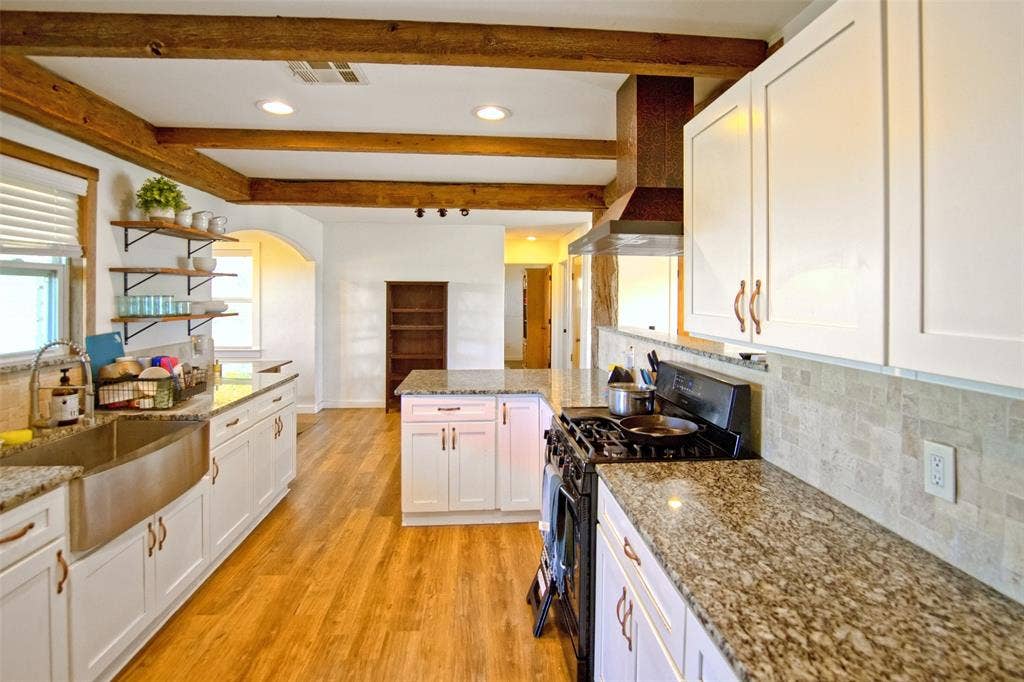 325 & 321 Grassy Way, Elm Mott, TX 76640 Kitchen featuring white shaker cabinetry, stone countertops, exposed wood ceiling beams, wood-finish flooring, and a stainless steel farmhouse sink