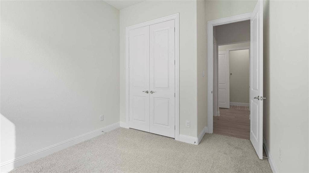 Neutral-toned carpeting, white two-panel closet doors with satin nickel hardware, and a matching interior door with a lever handle