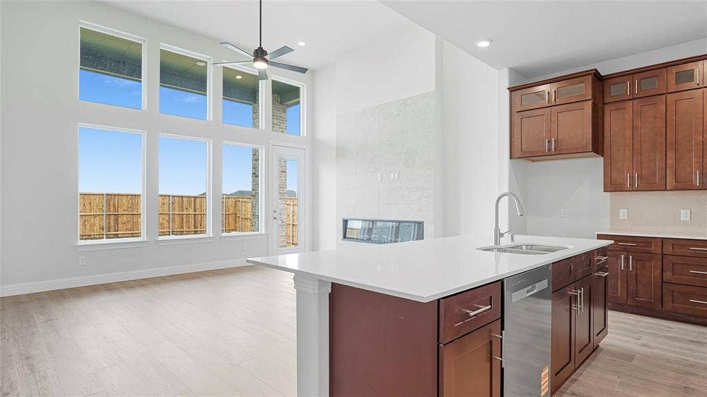 Open-concept area featuring high ceilings, wood-finish flooring, a kitchen island with stone-surface countertop, cabinetry with metal hardware, and floor-to-ceiling windows