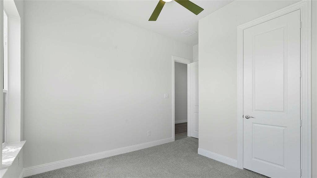 Neutral-toned interior featuring wall-to-wall carpeting, a multi-panel interior door, and a ceiling fan
