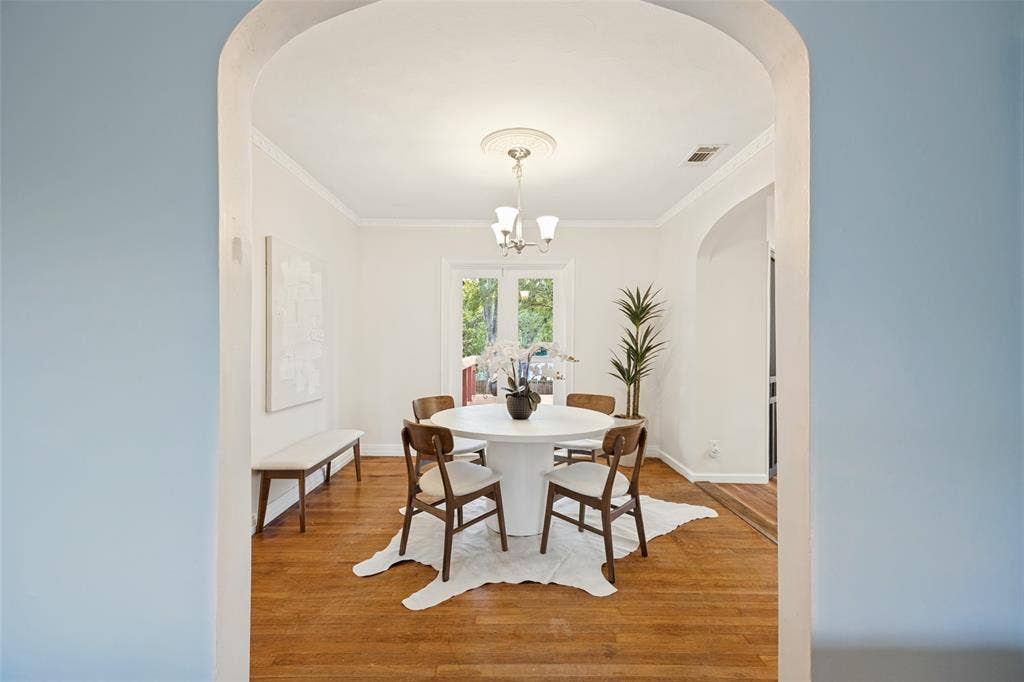 7011 Hammond Avenue, Dallas, TX 75223 Arched doorway entry into a room featuring wood-finish flooring, crown molding, a central ceiling medallion with a multi-light fixture, and glass-paned doors
