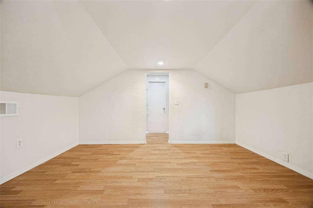 7011 Hammond Avenue, Dallas, TX 75223 Interior room featuring vaulted ceilings, wood-finish flooring, and a single recessed light fixture