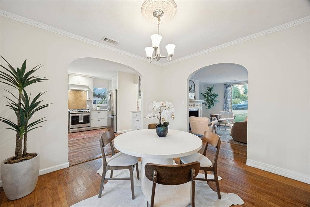 7011 Hammond Avenue, Dallas, TX 75223 Dining area featuring arched entryways, wood-finish flooring, crown molding, and a decorative ceiling medallion with a three-light chandelier
