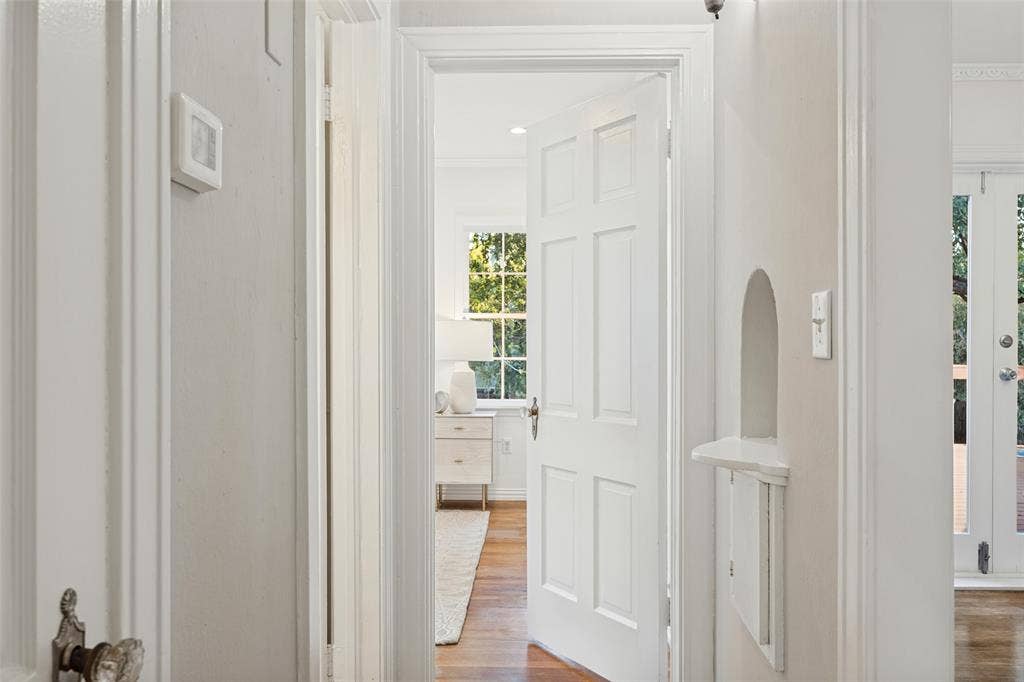 7011 Hammond Avenue, Dallas, TX 75223 Six-panel interior door with traditional hardware, arched architectural wall niche, wood-finish flooring, and double-paned multi-light window