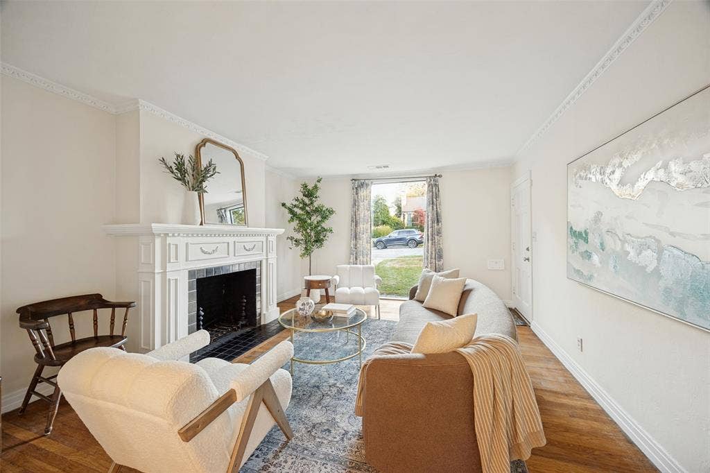 7011 Hammond Avenue, Dallas, TX 75223 Living area featuring wood-finish flooring, crown molding, and a fireplace with a white mantel and tile hearth