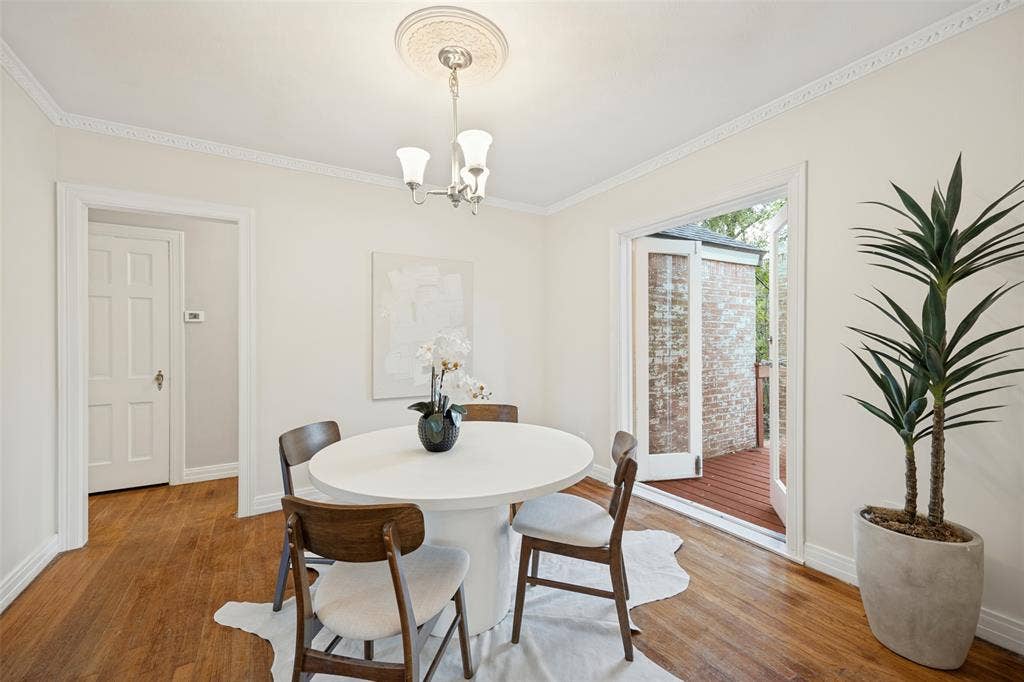 7011 Hammond Avenue, Dallas, TX 75223 Wood-finish flooring, crown molding, ceiling medallion with a three-light chandelier, and glass-paneled double doors opening to a wood-decked outdoor space