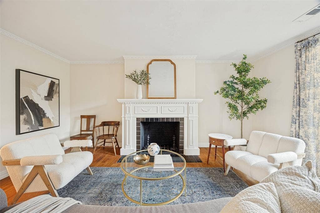 7011 Hammond Avenue, Dallas, TX 75223 Living area featuring a classic fireplace with white millwork surround, crown molding, and wood-finish flooring