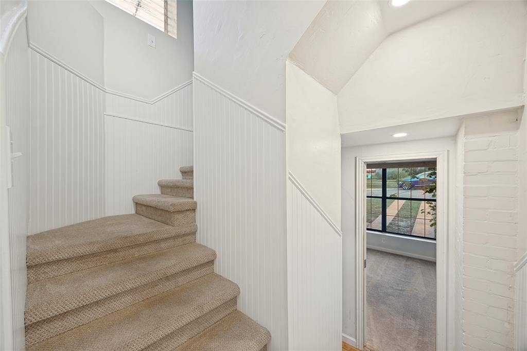 7011 Hammond Avenue, Dallas, TX 75223 Staircase featuring wall-to-wall carpeting and beadboard wainscoting, accented by a painted brick wall and recessed lighting