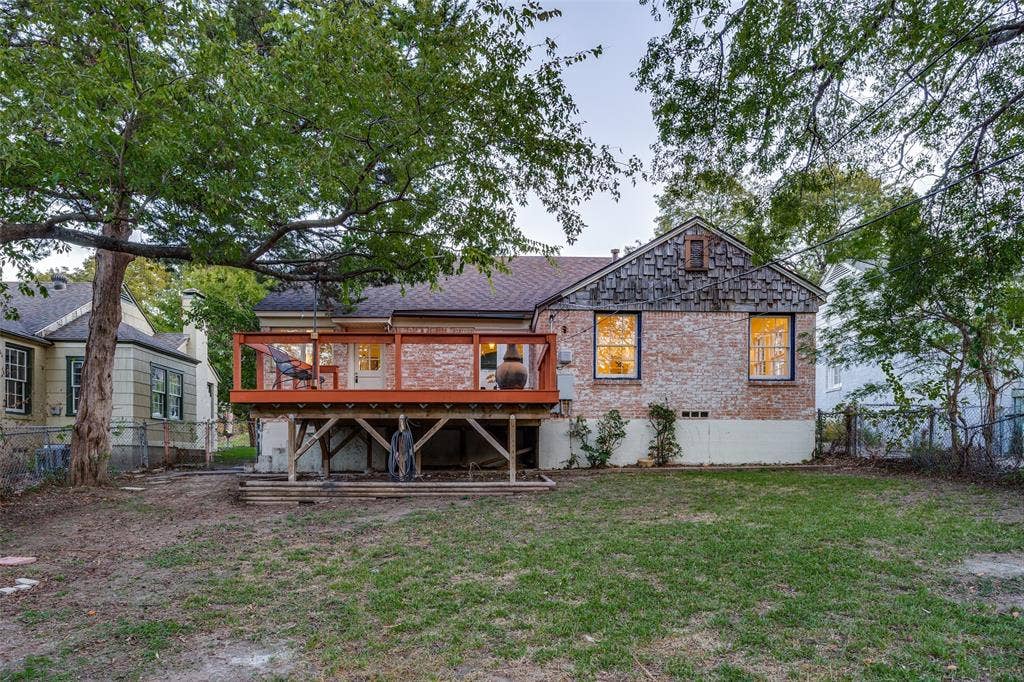 7011 Hammond Avenue, Dallas, TX 75223 Rear exterior featuring a brick facade with shingle-style siding, an elevated wood deck, and a fenced backyard