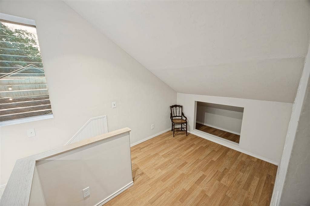 7011 Hammond Avenue, Dallas, TX 75223 Interior space featuring vaulted ceilings, wood-finish flooring, a rectangular wall-recessed storage area, and a large window