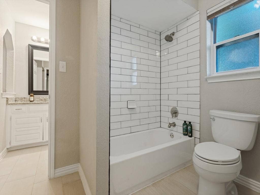 900 Lexington Drive, Plano, TX 75075 Bathroom featuring a white subway tile shower surround, tub with chrome fixtures, and stone-finish vanity countertop