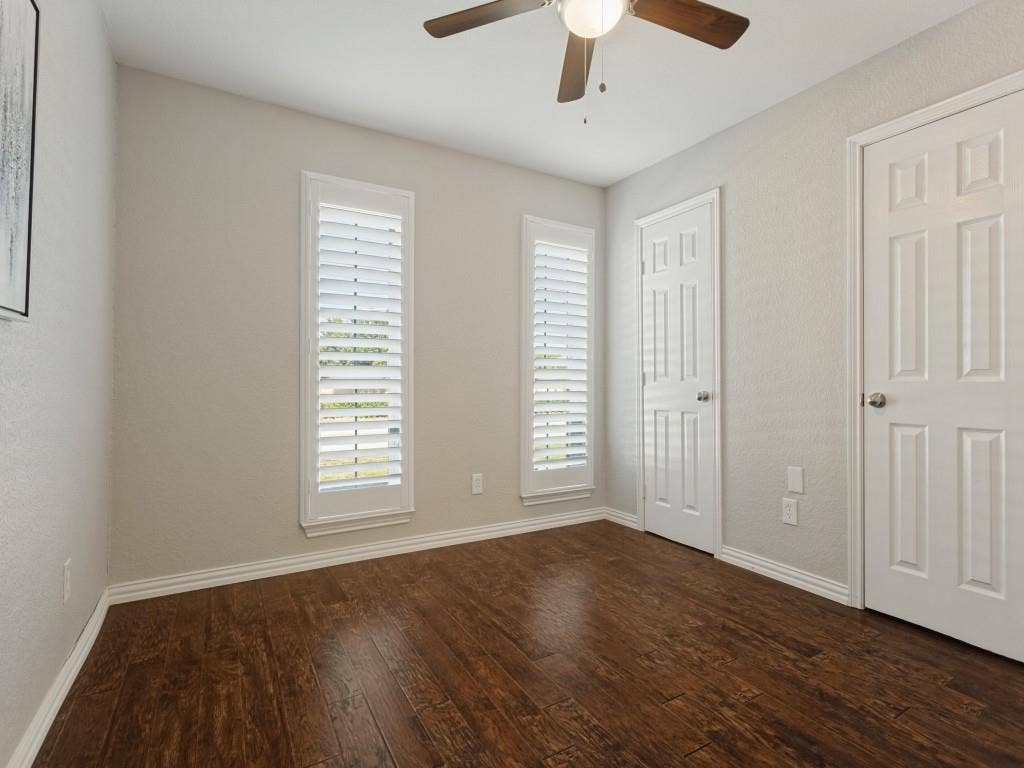 900 Lexington Drive, Plano, TX 75075 Wood-finish flooring, white plantation shutters, neutral wall color, and a ceiling-mounted light fixture with a fan