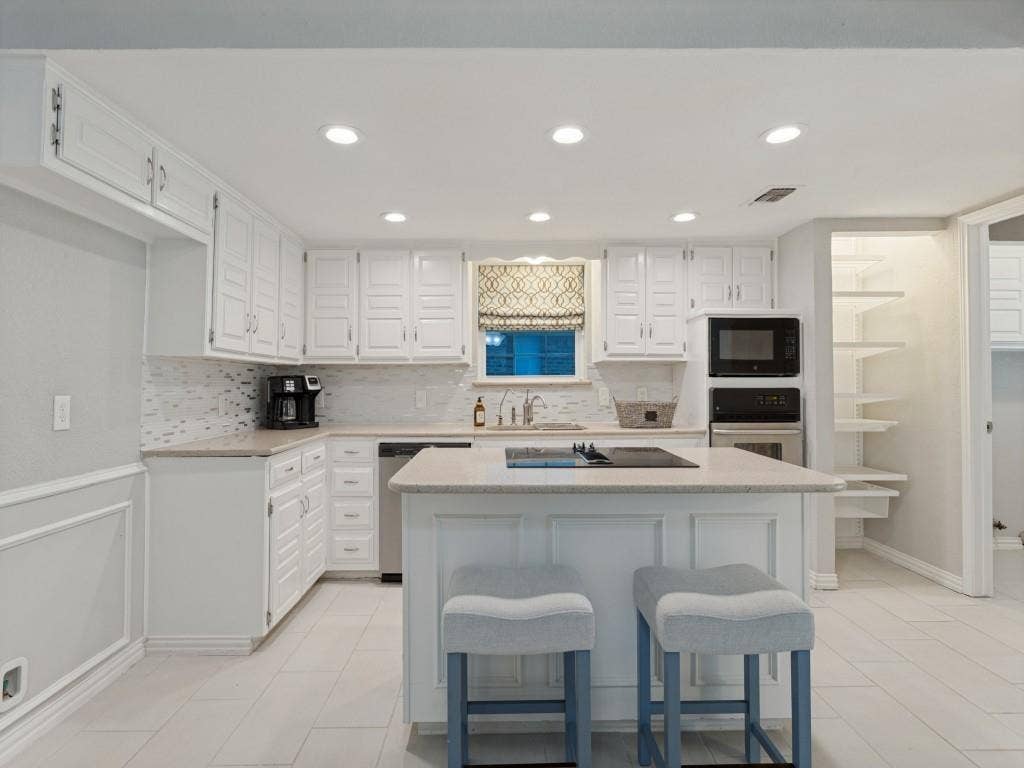 900 Lexington Drive, Plano, TX 75075 Kitchen featuring white cabinetry, center island with cooktop, neutral stone-composite countertops, tile flooring, and integrated wall oven and microwave
