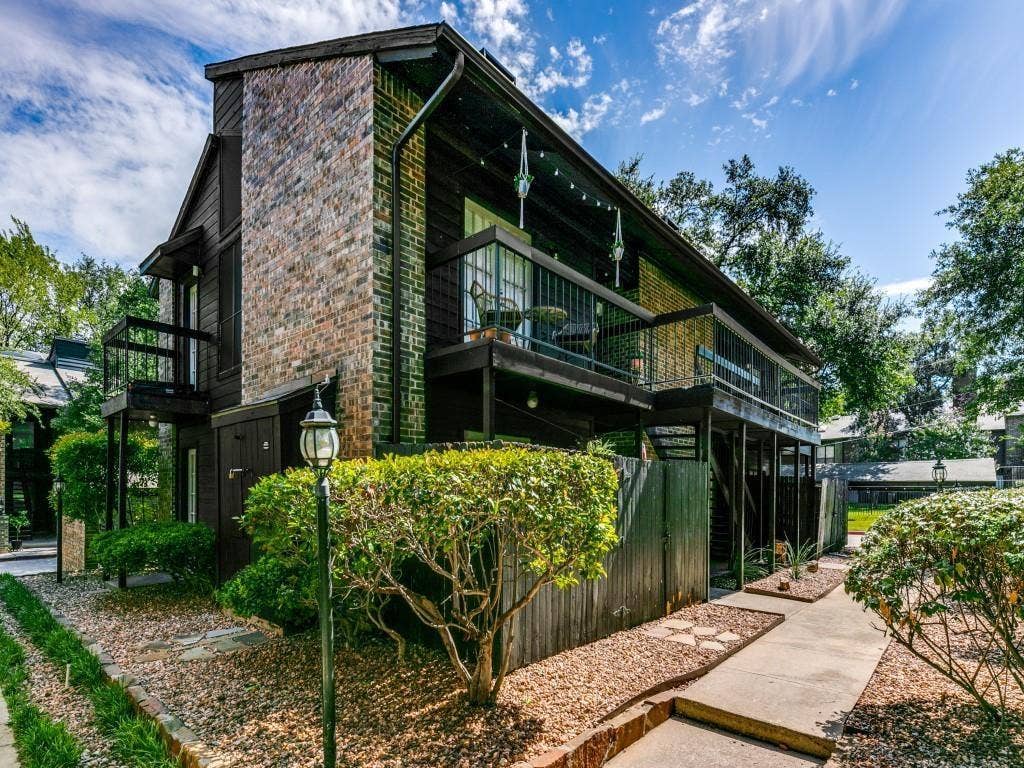7525 Holly Hill Drive, #20, Dallas, TX 75231 Multi-story exterior featuring multi-toned brick masonry, horizontal wood siding, second-level balcony, and concrete walkway