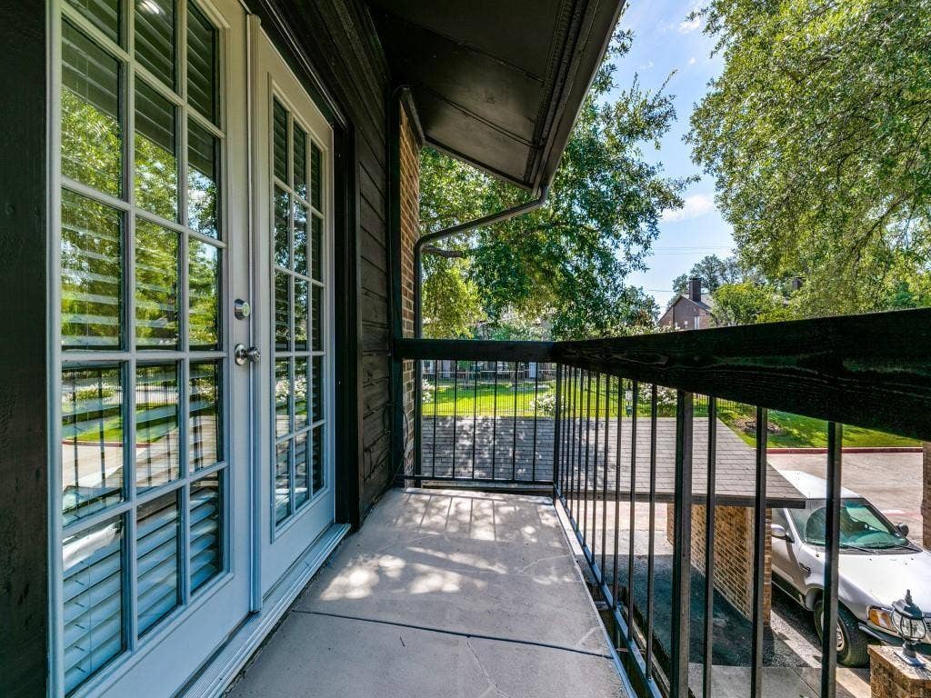 7525 Holly Hill Drive, #20, Dallas, TX 75231 Covered balcony featuring white-frame French doors, concrete flooring, and black metal railings