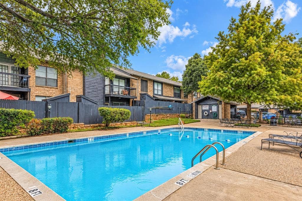 7525 Holly Hill Drive, #20, Dallas, TX 75231 Outdoor swimming pool featuring a concrete deck, metal handrails, and surrounding landscaping with mature trees