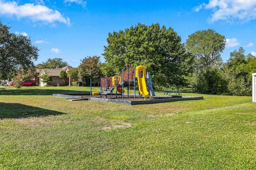 6821 Douglas Creek, Plano, TX 75023 Expansive backyard featuring a dedicated playground structure, mulch-lined recreation area, mature trees, and open green space