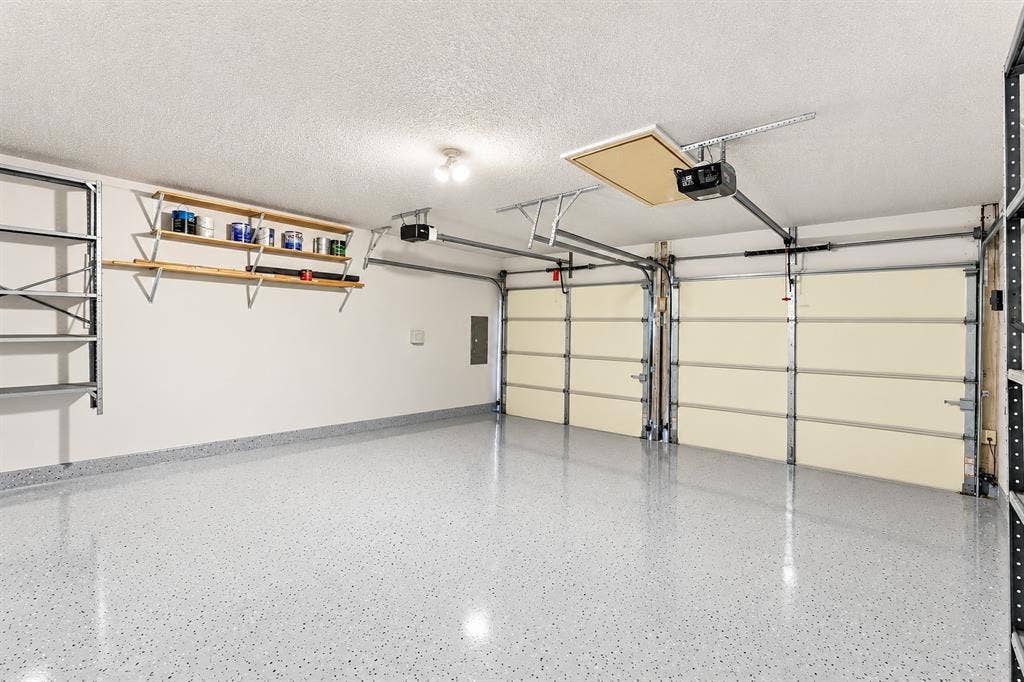 6821 Douglas Creek, Plano, TX 75023 Two-car garage featuring epoxy-coated flooring, built-in wall shelving, an automatic door opener system, and attic access
