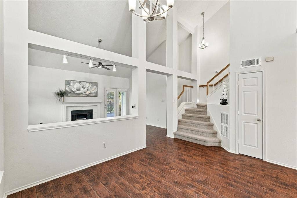 6821 Douglas Creek, Plano, TX 75023 Vaulted ceilings featuring multi-tiered architectural cutouts, wood-finish flooring, a built-in fireplace with a mantel, and a carpeted staircase with a wood handrail